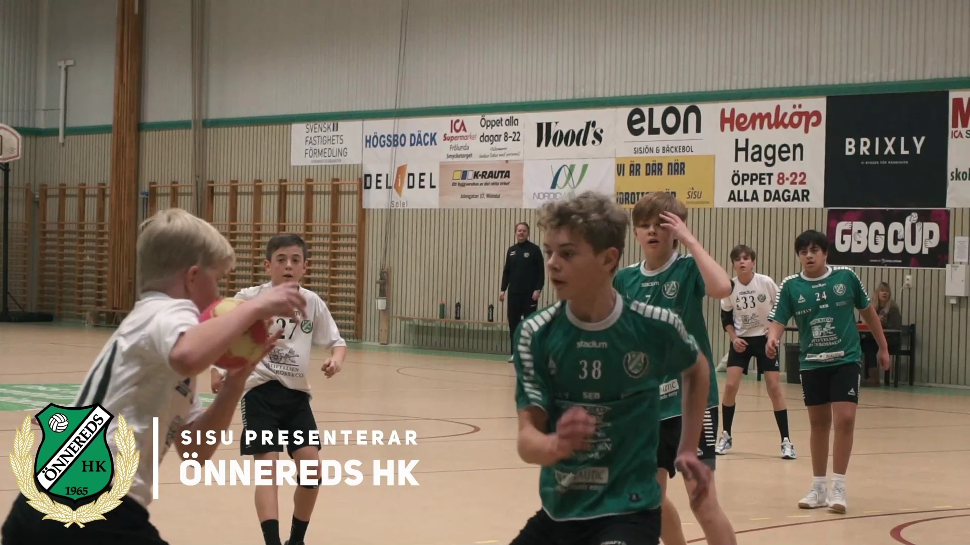 Unga handbollsspelare i gröna och vita tröjor i en idrottshall, med texten ”SISU presenterar Önnereds HK” och klubbens märke.
